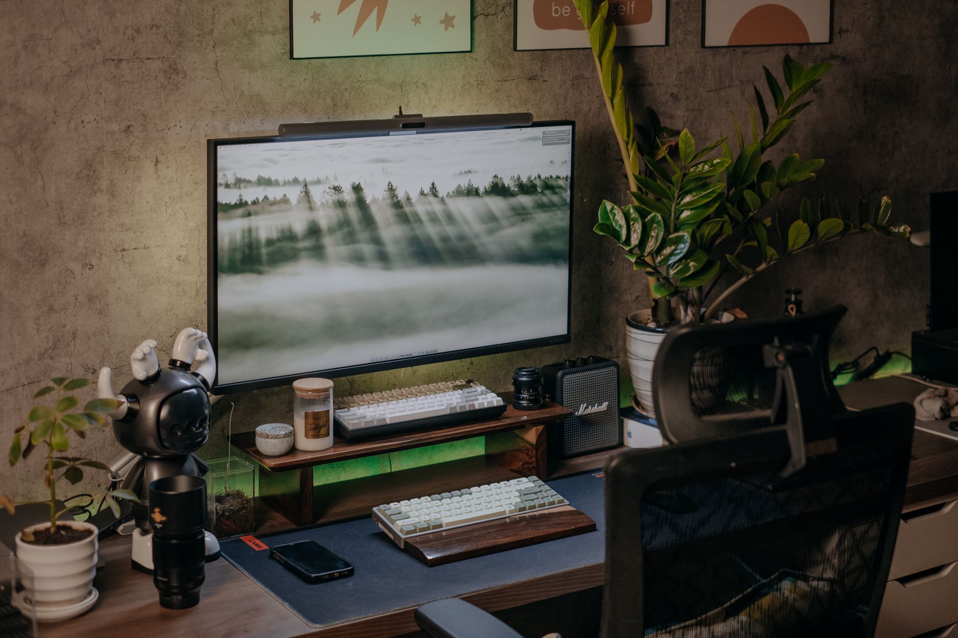 Stylish home office desk setup with monitor, plants, and ambient lighting.