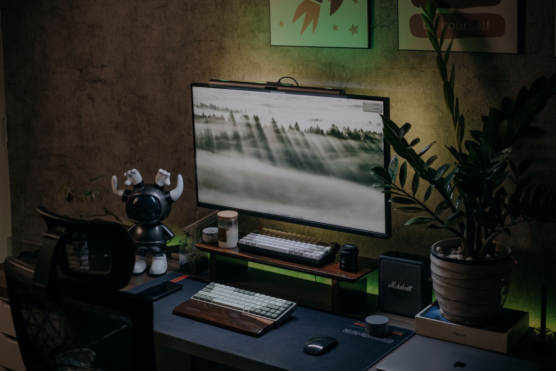 Cozy home office desk with monitor, keyboard, plants, and unique decor.