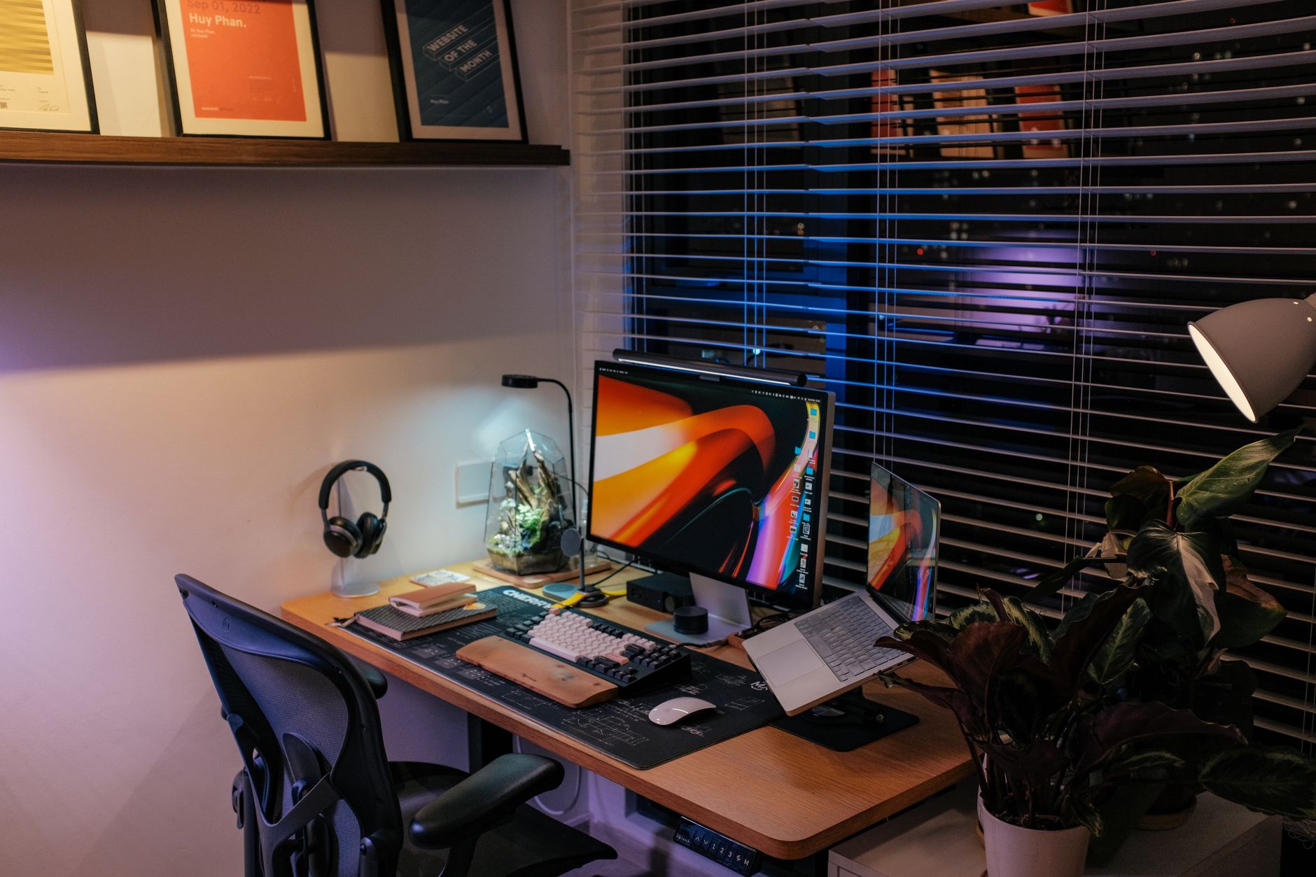 Cozy home office with a sleek computer setup, ambient lighting, and houseplants.